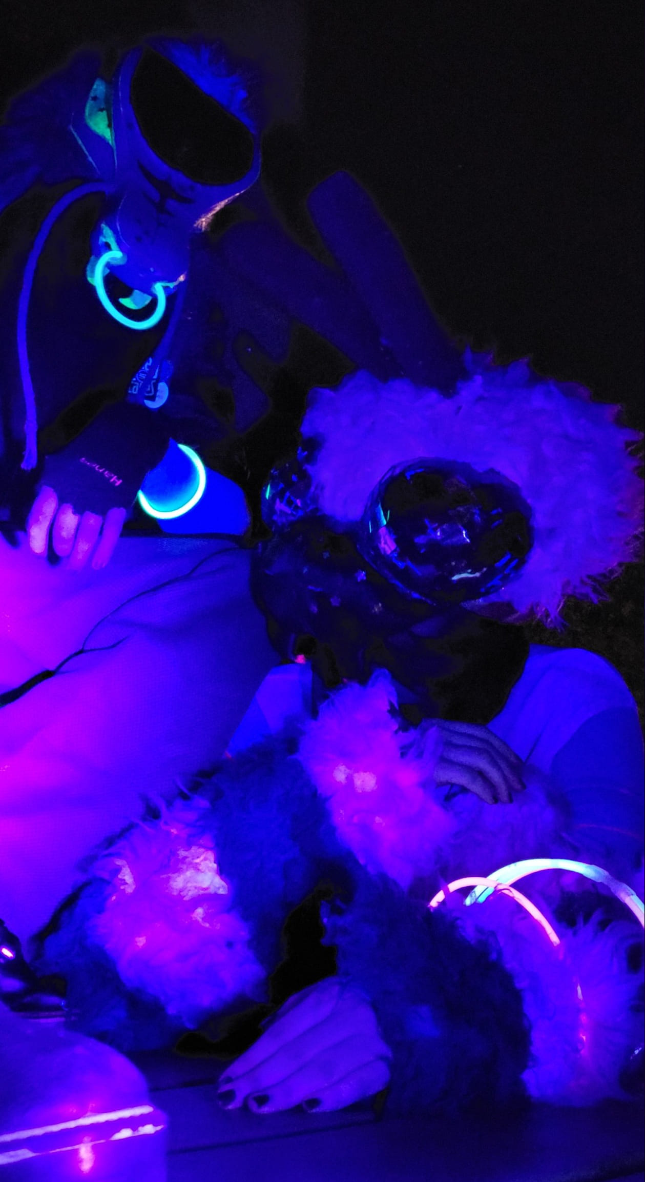 Both fursuiters posing together under the blacklight