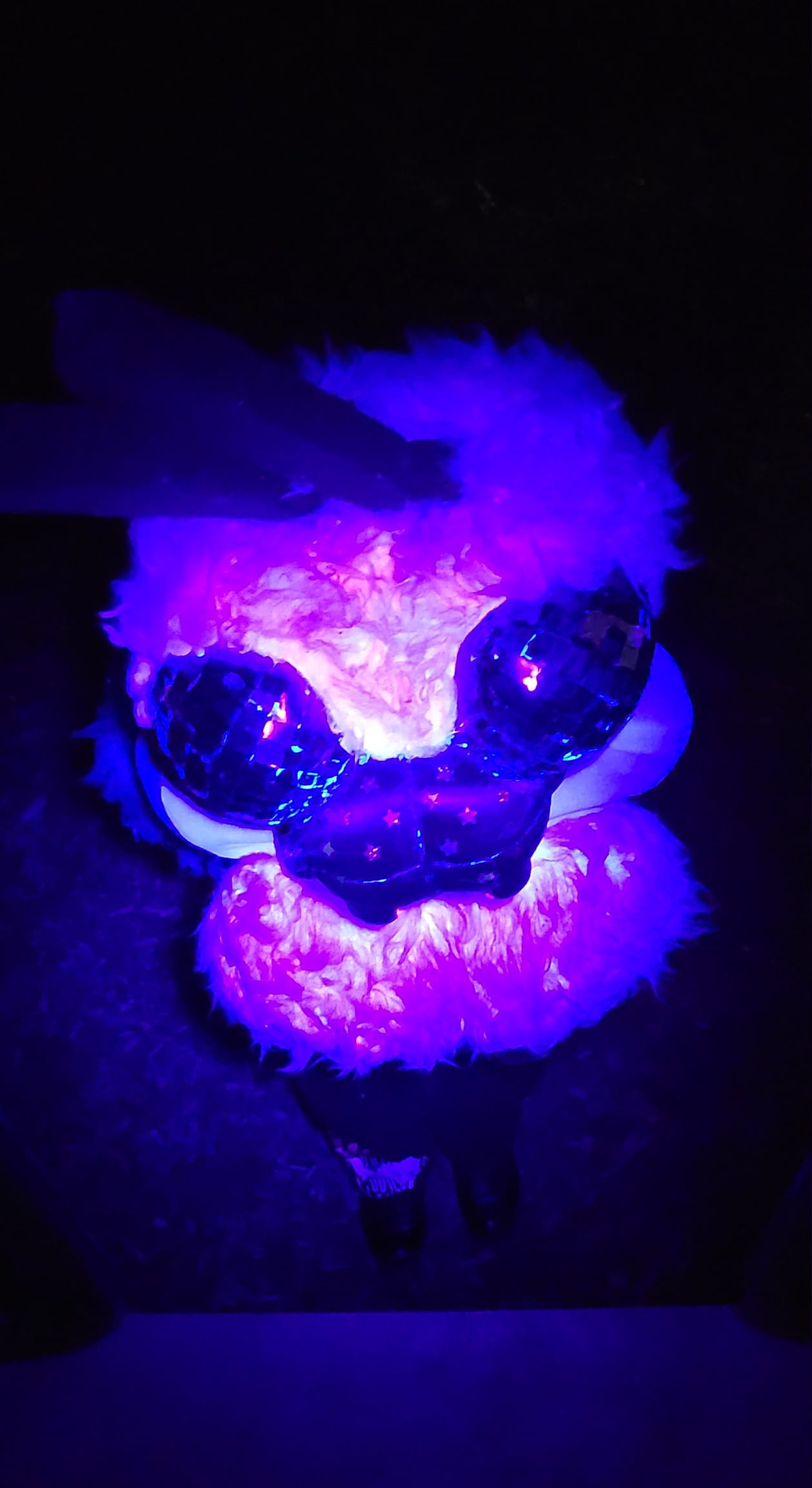 A blacklight image of the ant fursuit, angled from above.